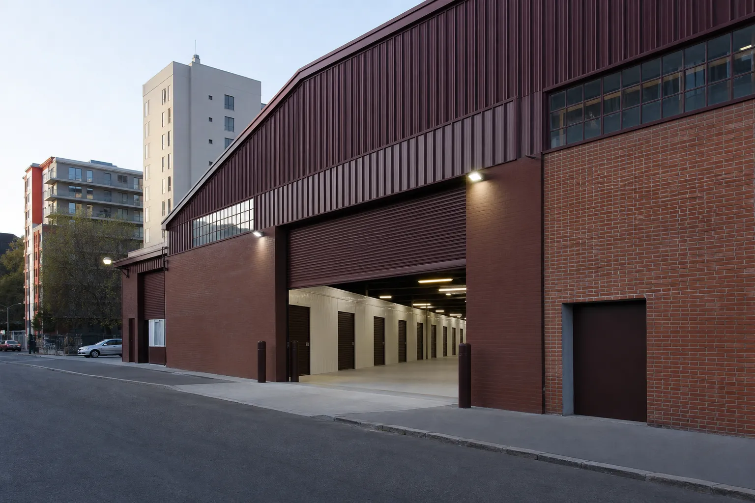 Façade en trois-quarts d’un site de stockage moderne en brique et acier, rideau métallique à demi relevé